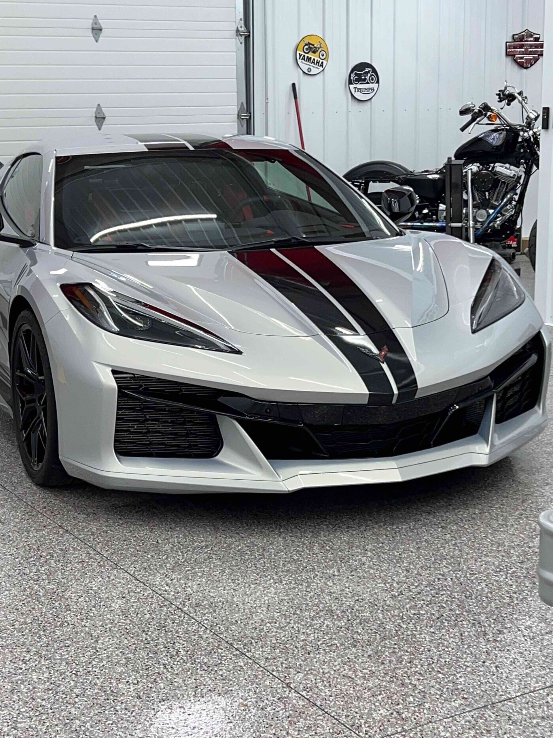 A person wearing black gloves is polishing a black car