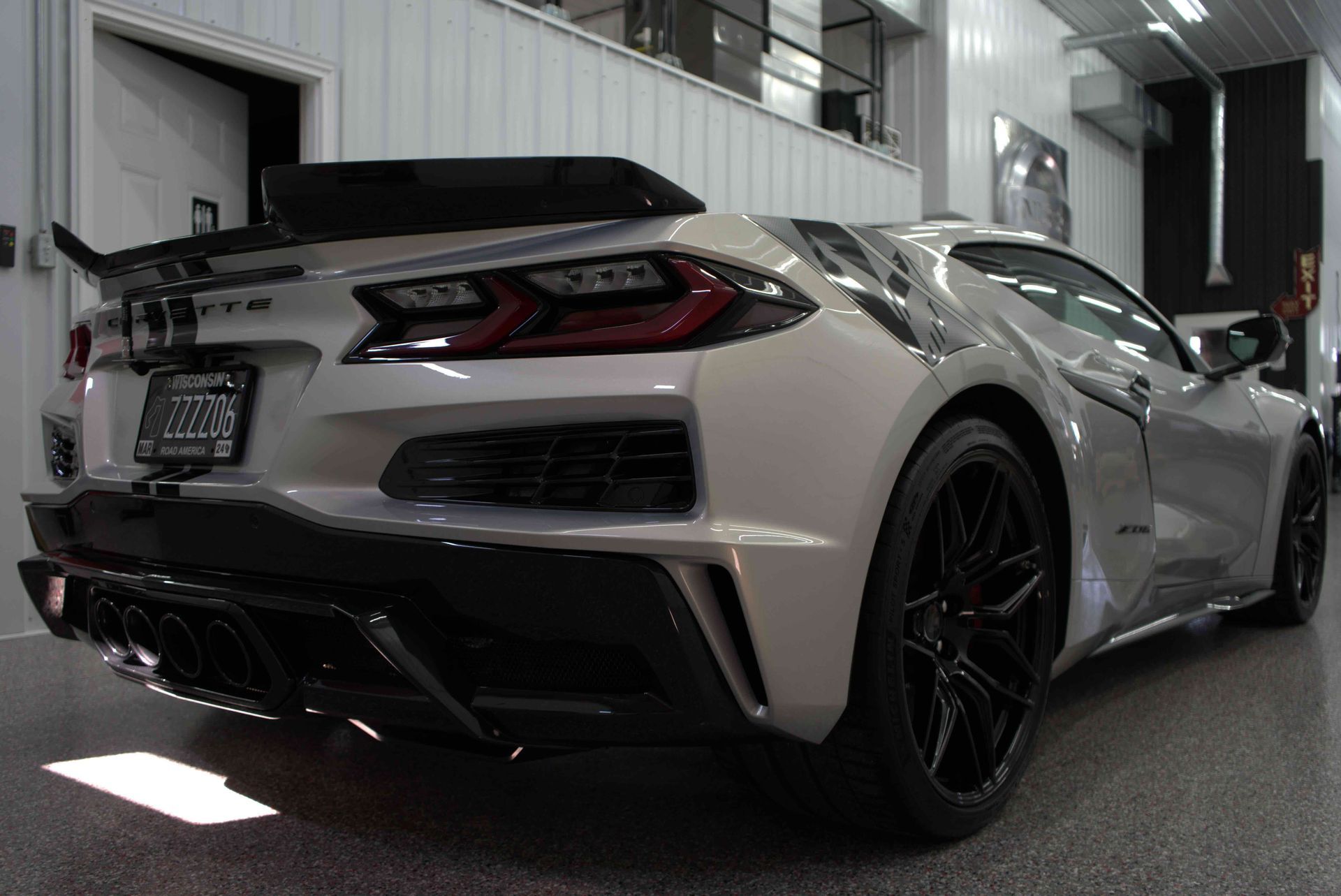 A man is cleaning the wheel of a black car with a sponge.