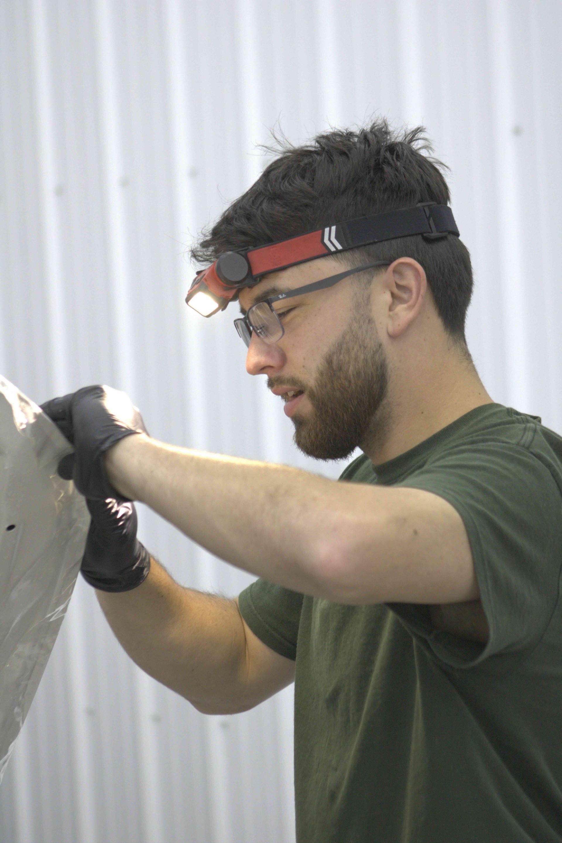 A person is cleaning a blue car with an orange towel