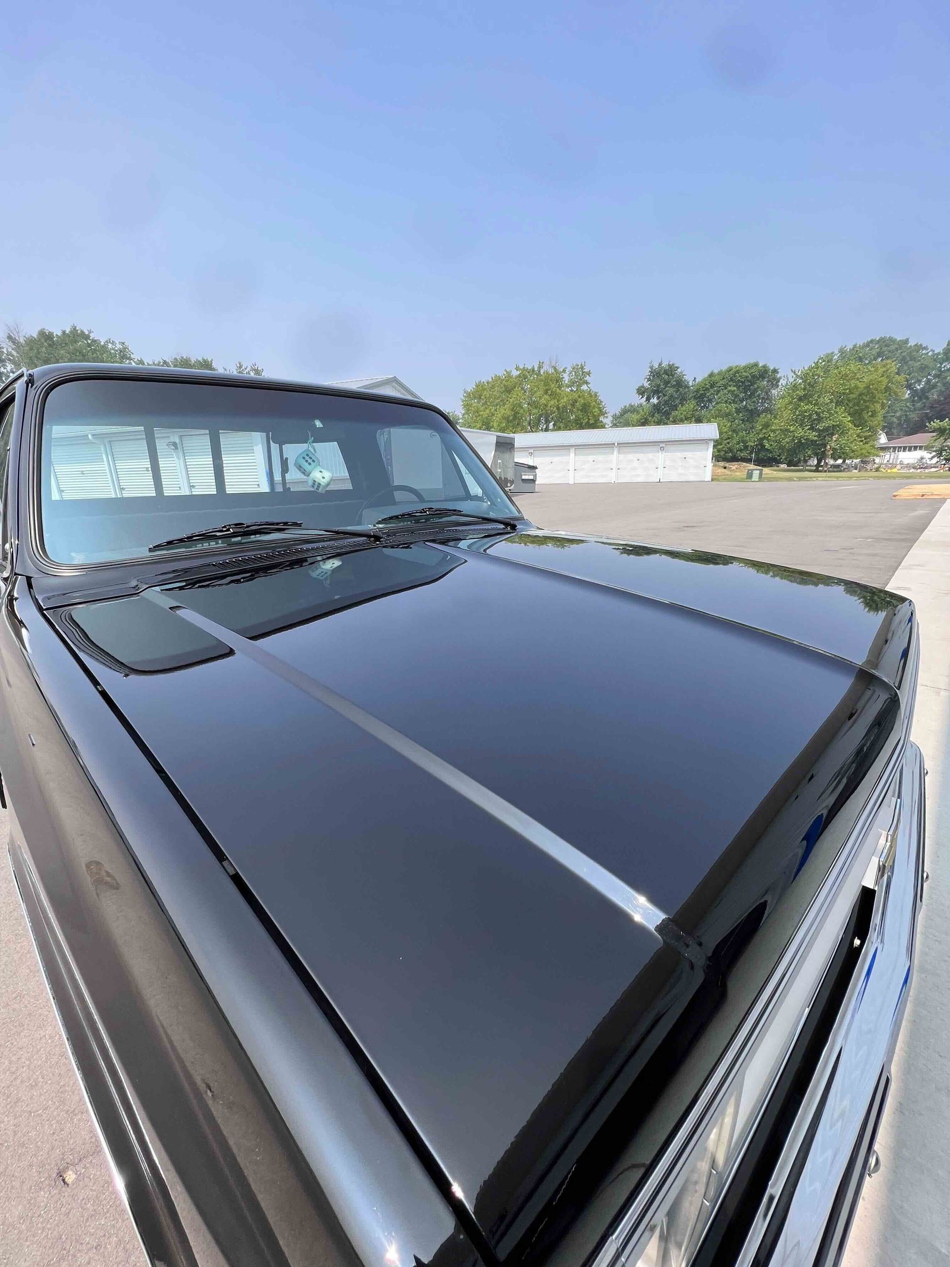 White pickup truck on a red hydraulic lift in a garage with a speckled floor and white walls.