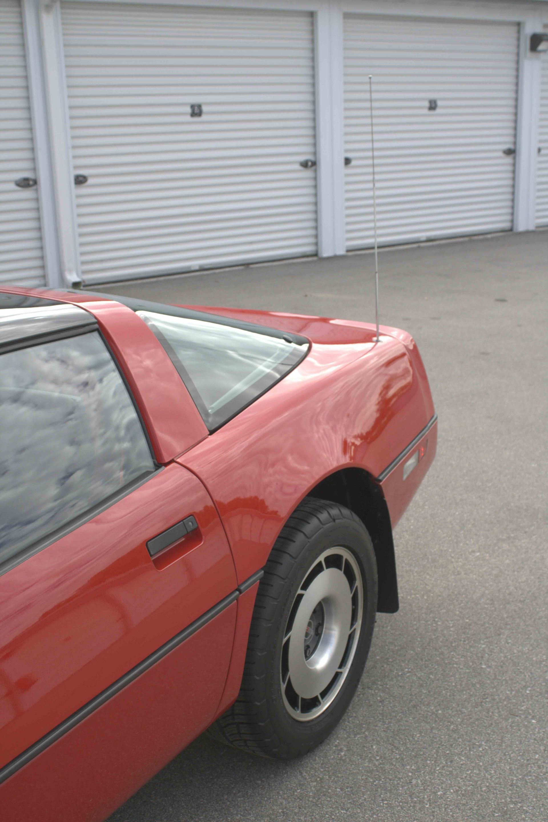 A person wearing black gloves is polishing a black car