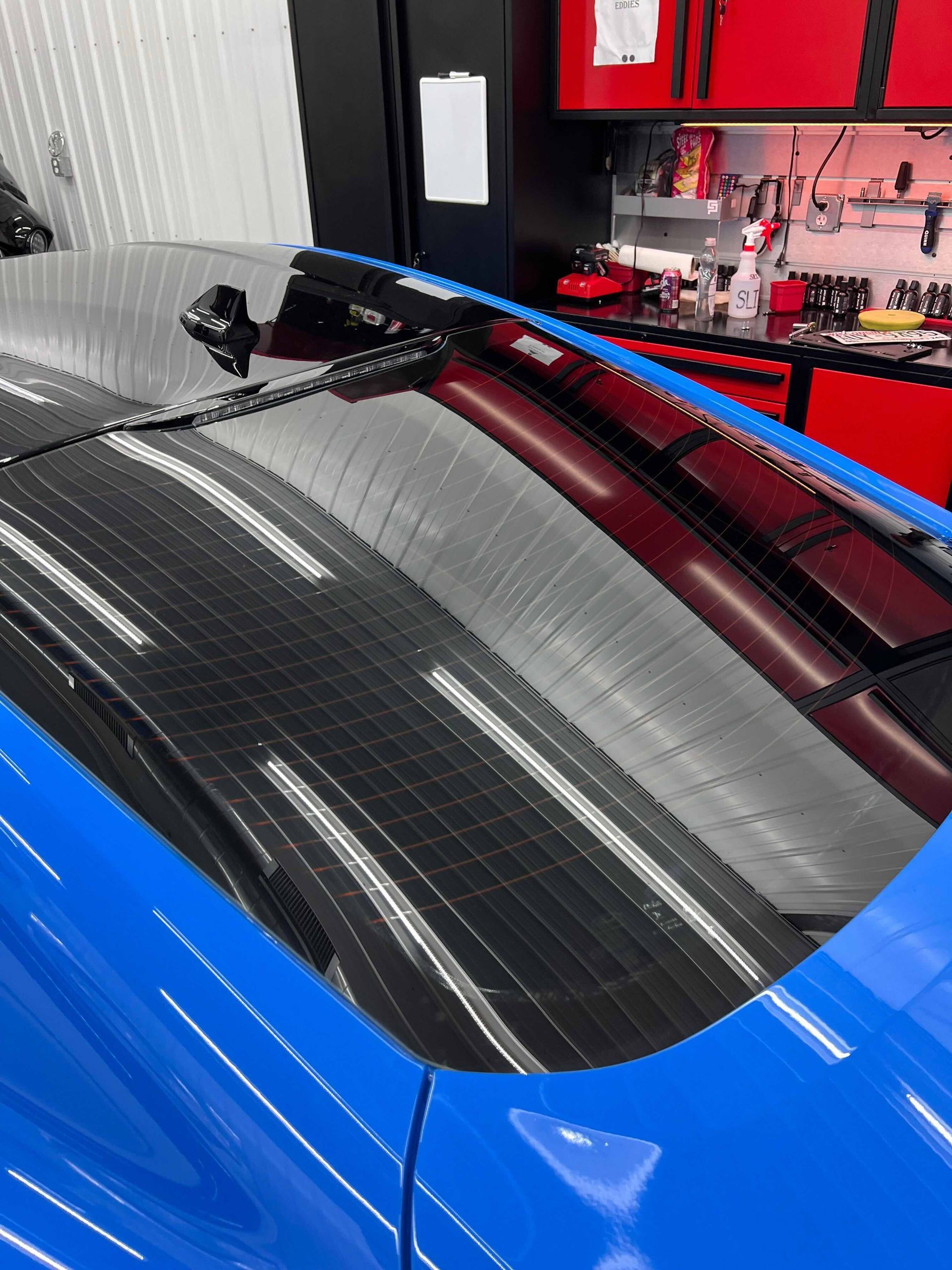 White pickup truck on a red hydraulic lift in a garage with a speckled floor and white walls.