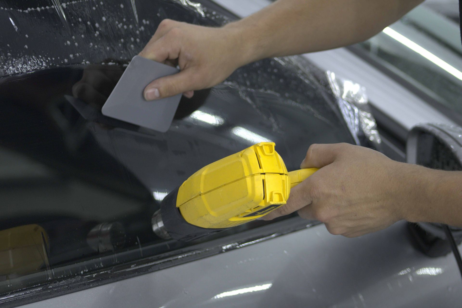 A man is cleaning the wheel of a black car with a sponge.