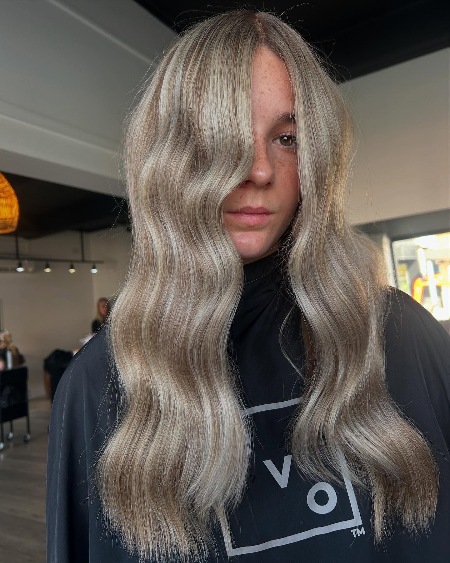 Woman with long, wavy, ash blonde hair in a salon setting.