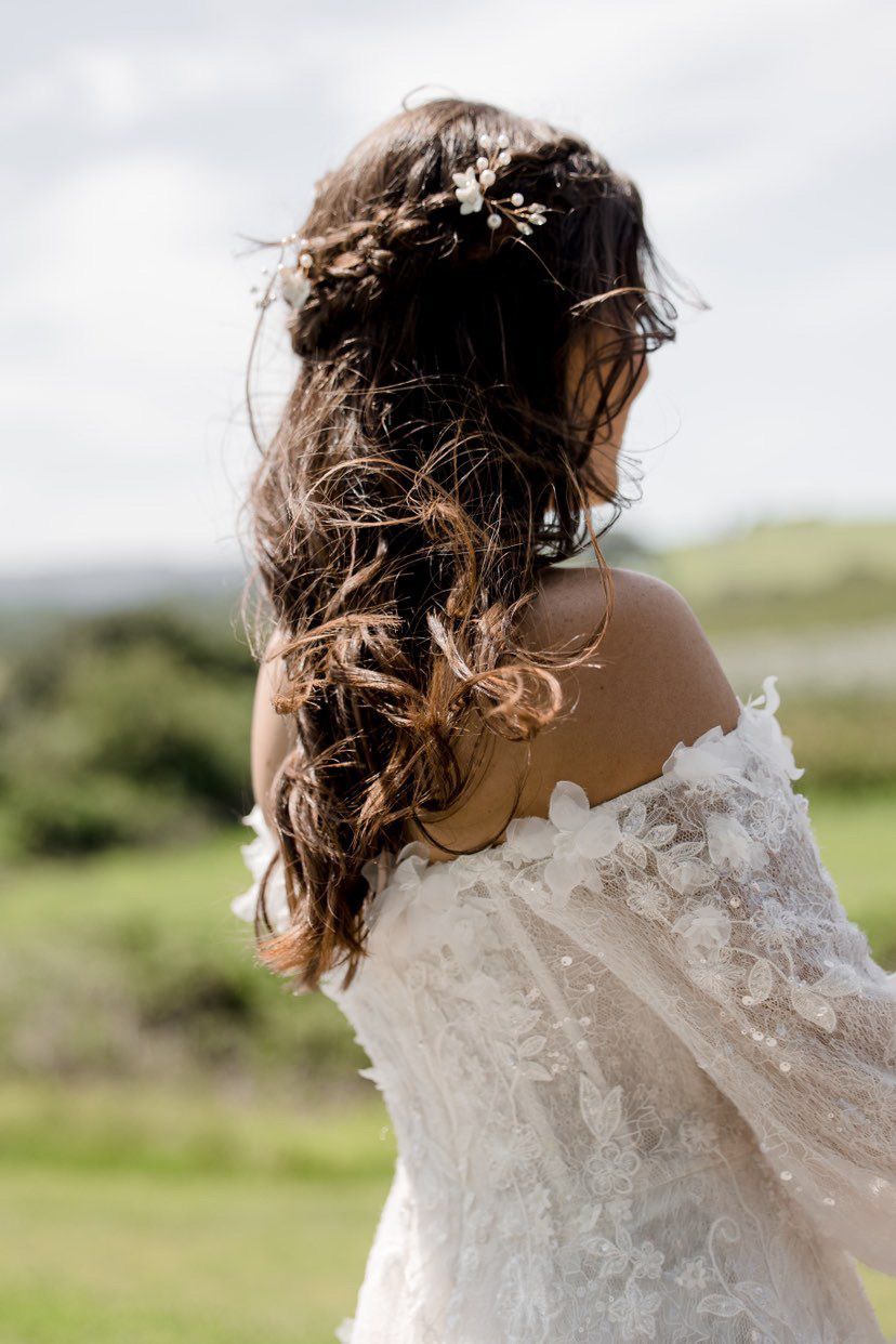 Woman with dark hair styled in a low bun, wearing a pink striped top.