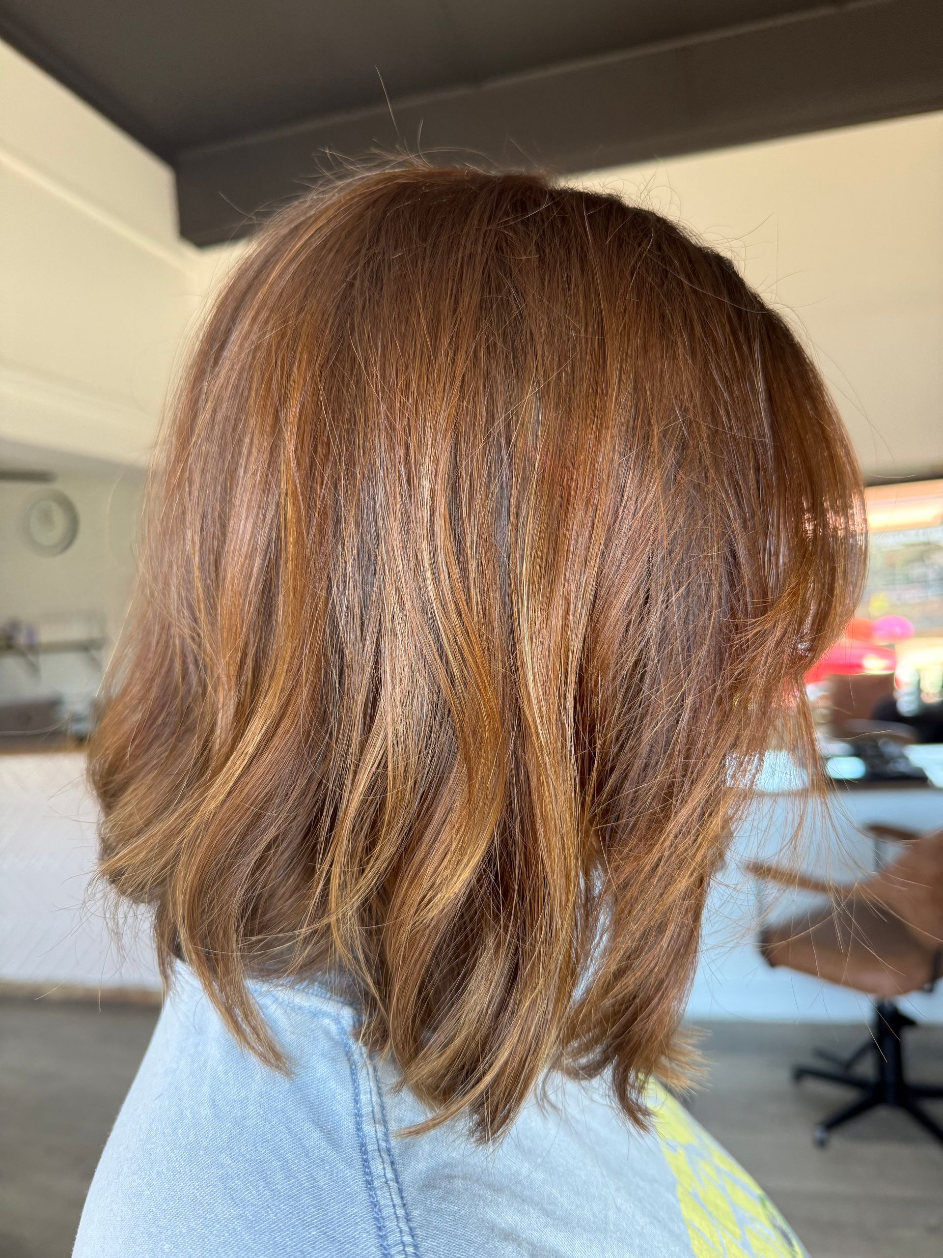 Woman with layered, reddish-brown hair; indoors.