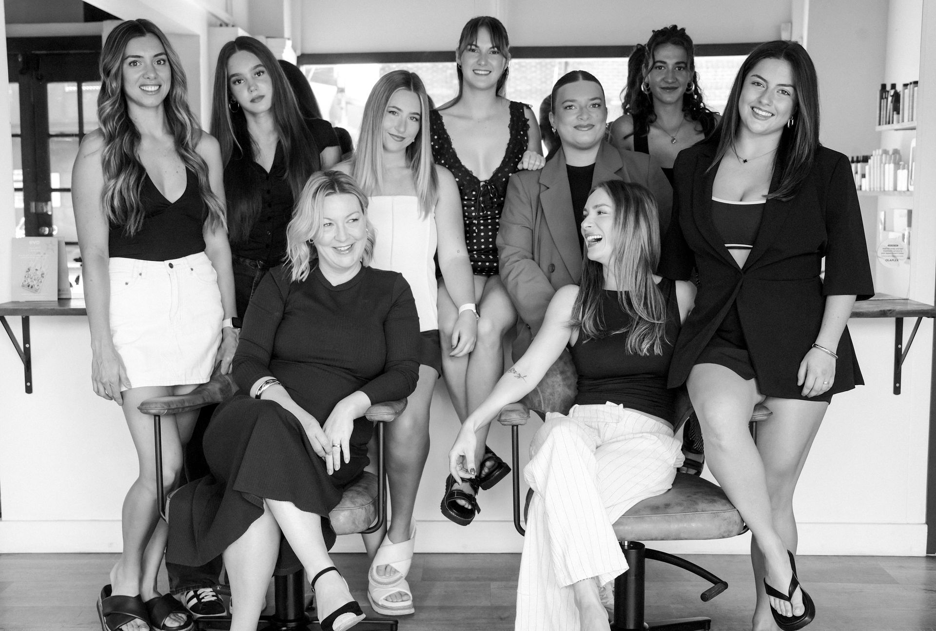 Woman with dark wavy hair wearing a black top and two necklaces.