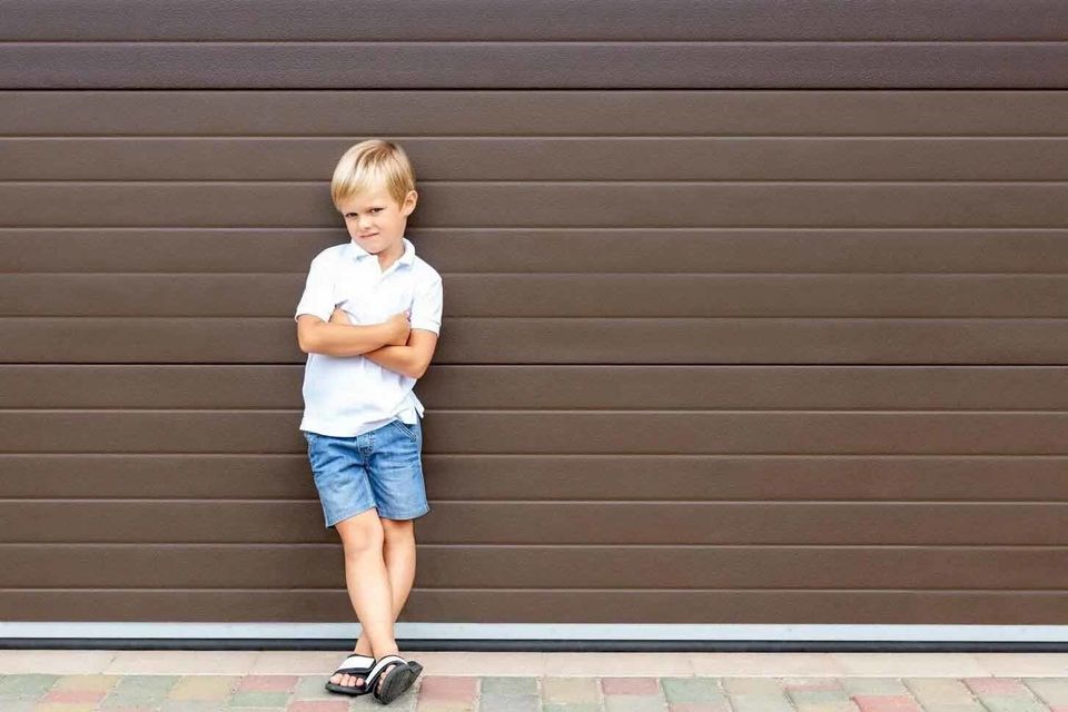 Maintenance — Boy Standing in Front of Garage Door in Signal Hill, CA