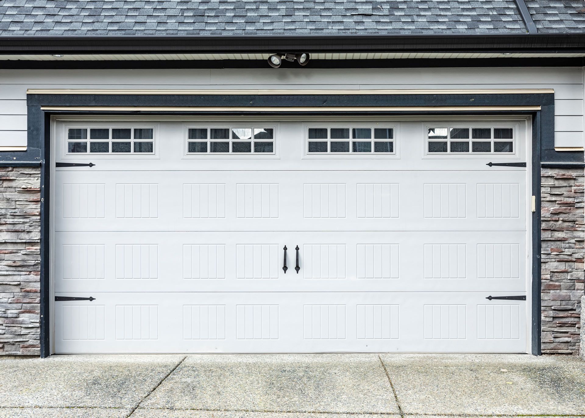 White double garage door with small top windows and black trim on a house exterior.
