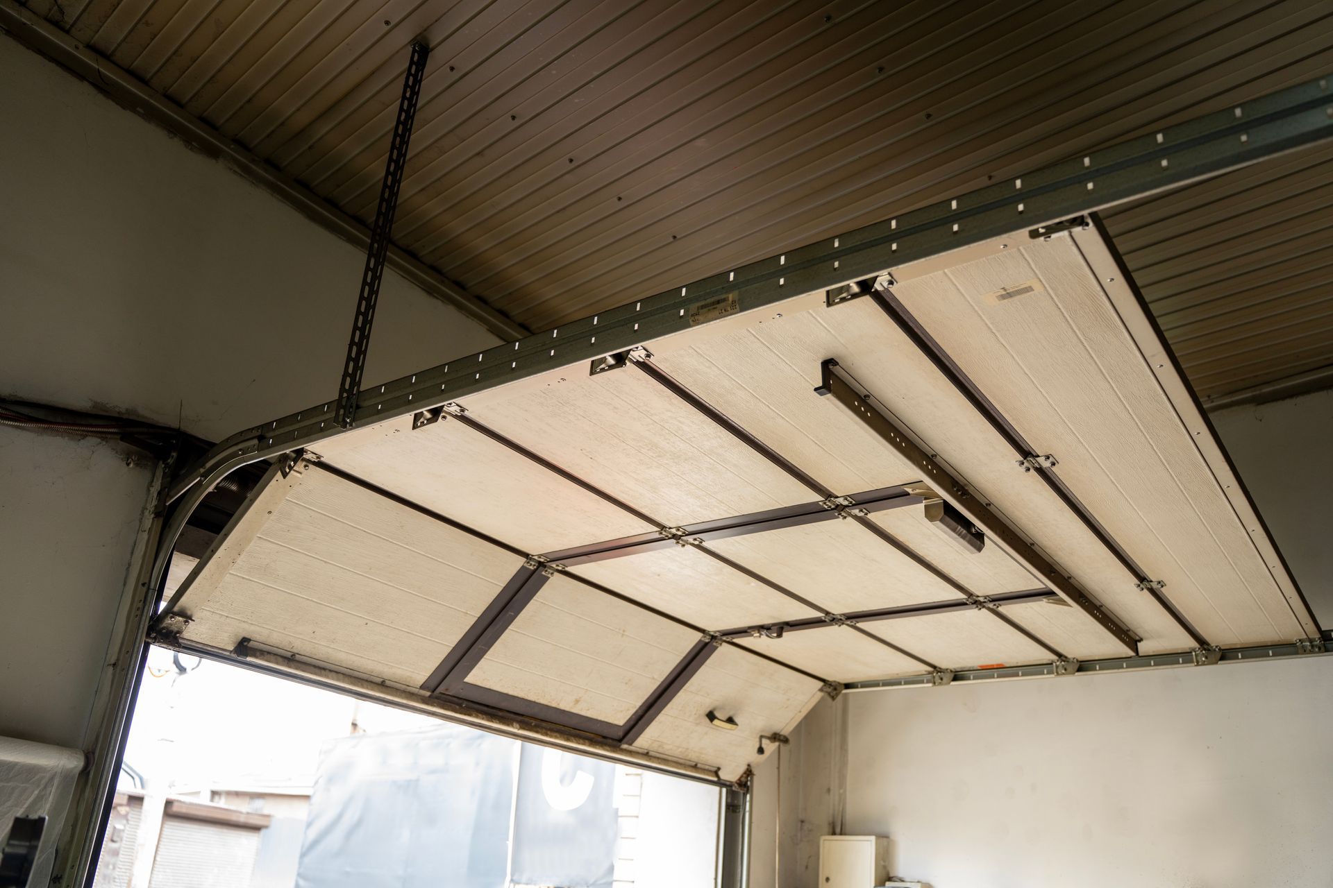 Garage door system installed inside residential garage with sectional overhead door panels-.