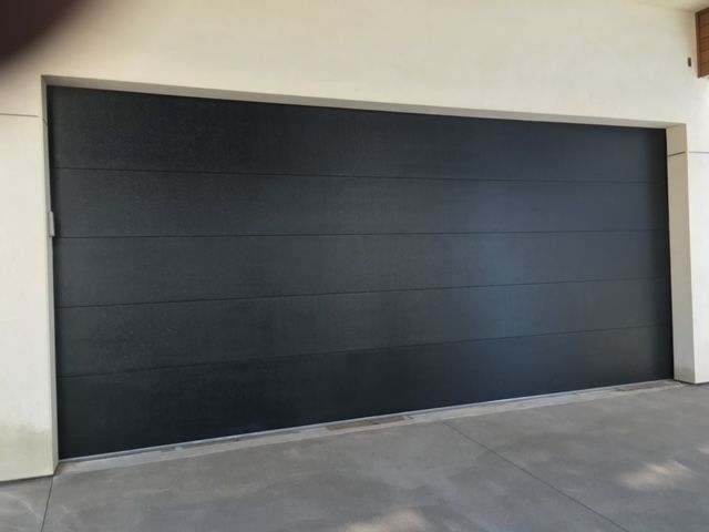 Black garage door, horizontal lines, gray concrete driveway, white trim.