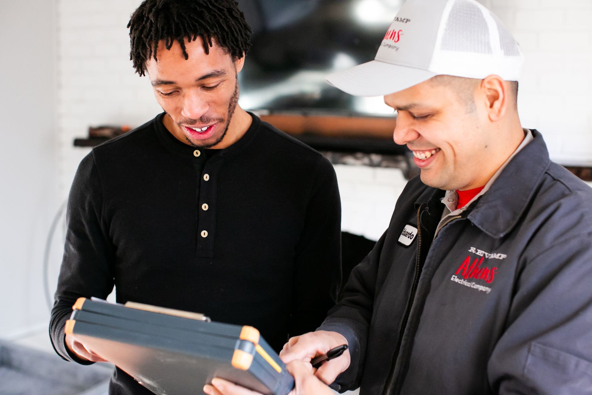 Two men looking at a tablet and smiling in a bright indoor setting