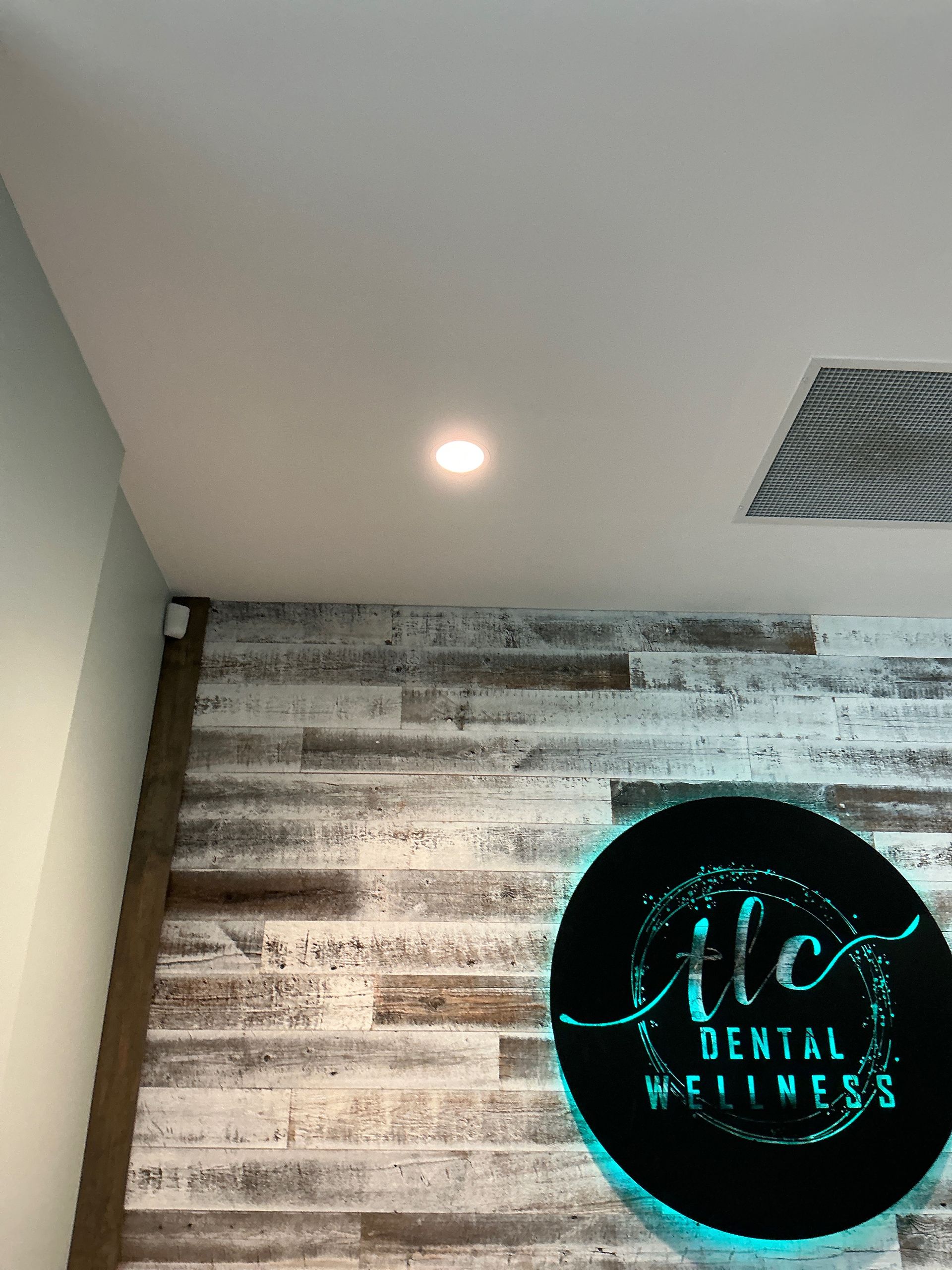 Dental wellness clinic sign on wood-paneled wall under a ceiling light