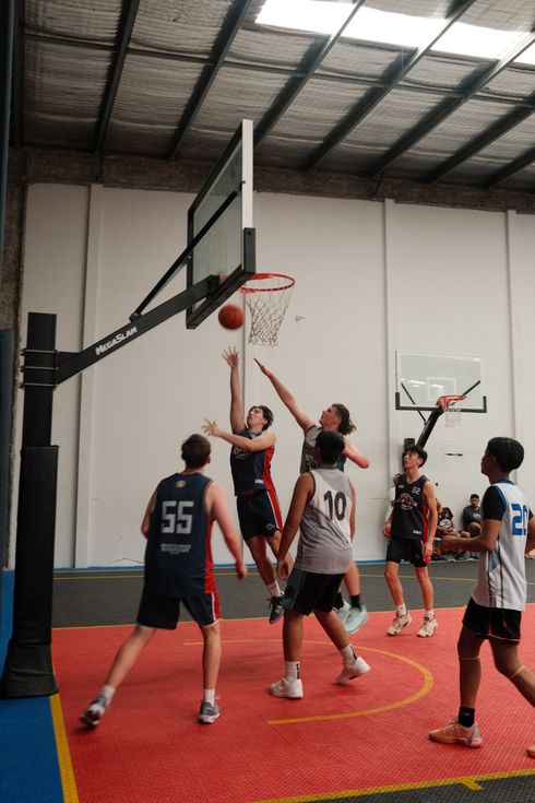 A group of young men are playing basketball in a gym.