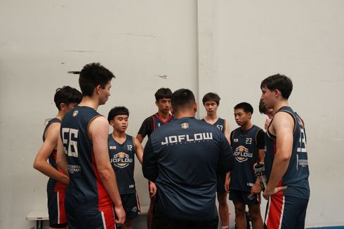 A group of young men in basketball uniforms are standing in a huddle.
