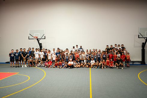A large group of people are posing for a picture on a basketball court.
