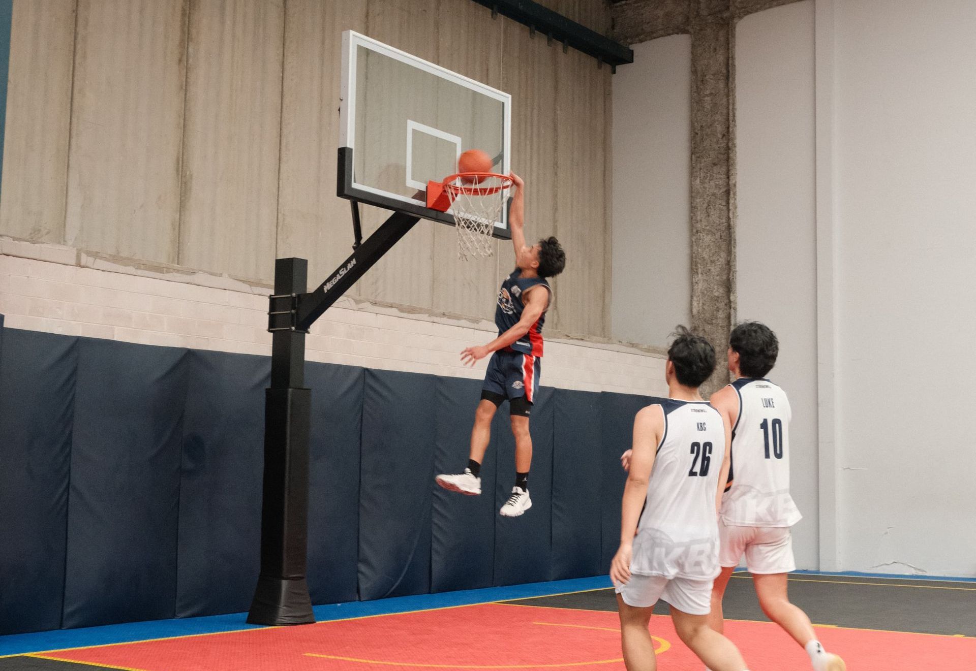 A group of basketball players are playing basketball in a gym.