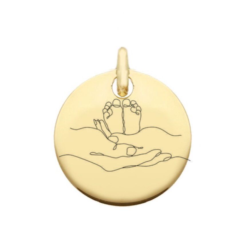 Ciondolo circolare in oro con disegno lineare di piedini di bambino in mani a coppa.