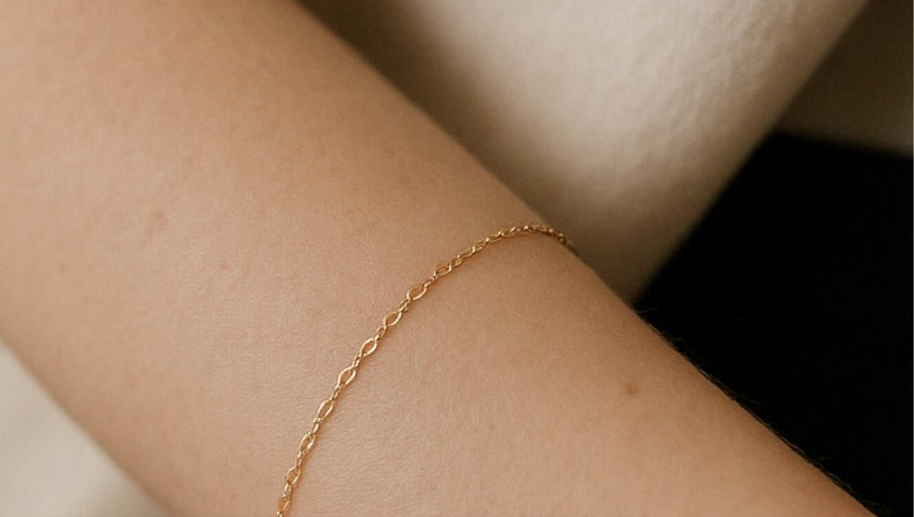 Delicato bracciale a catena d'oro su un braccio dalla pelle chiara.