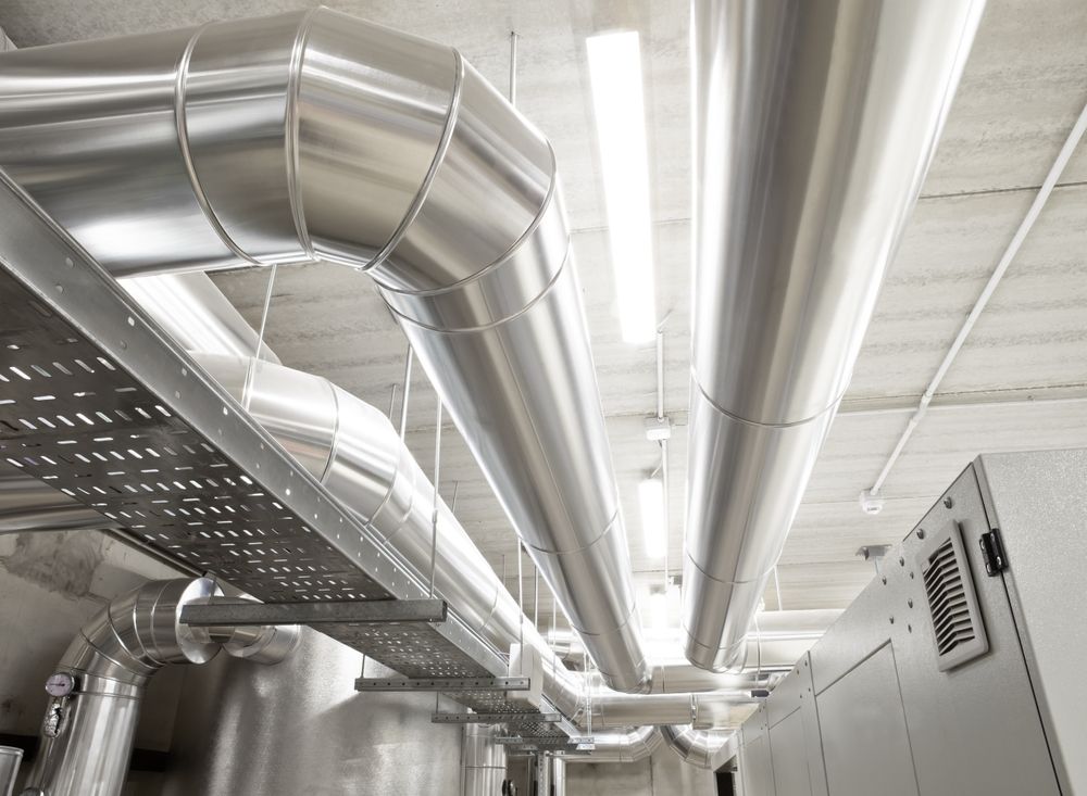 A bunch of stainless steel pipes are hanging from the ceiling of a building.