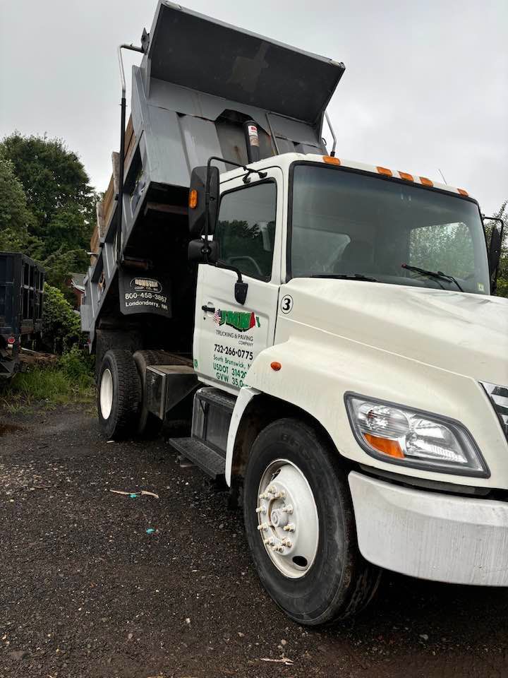 White dump truck with raised bed, parked on gravel.