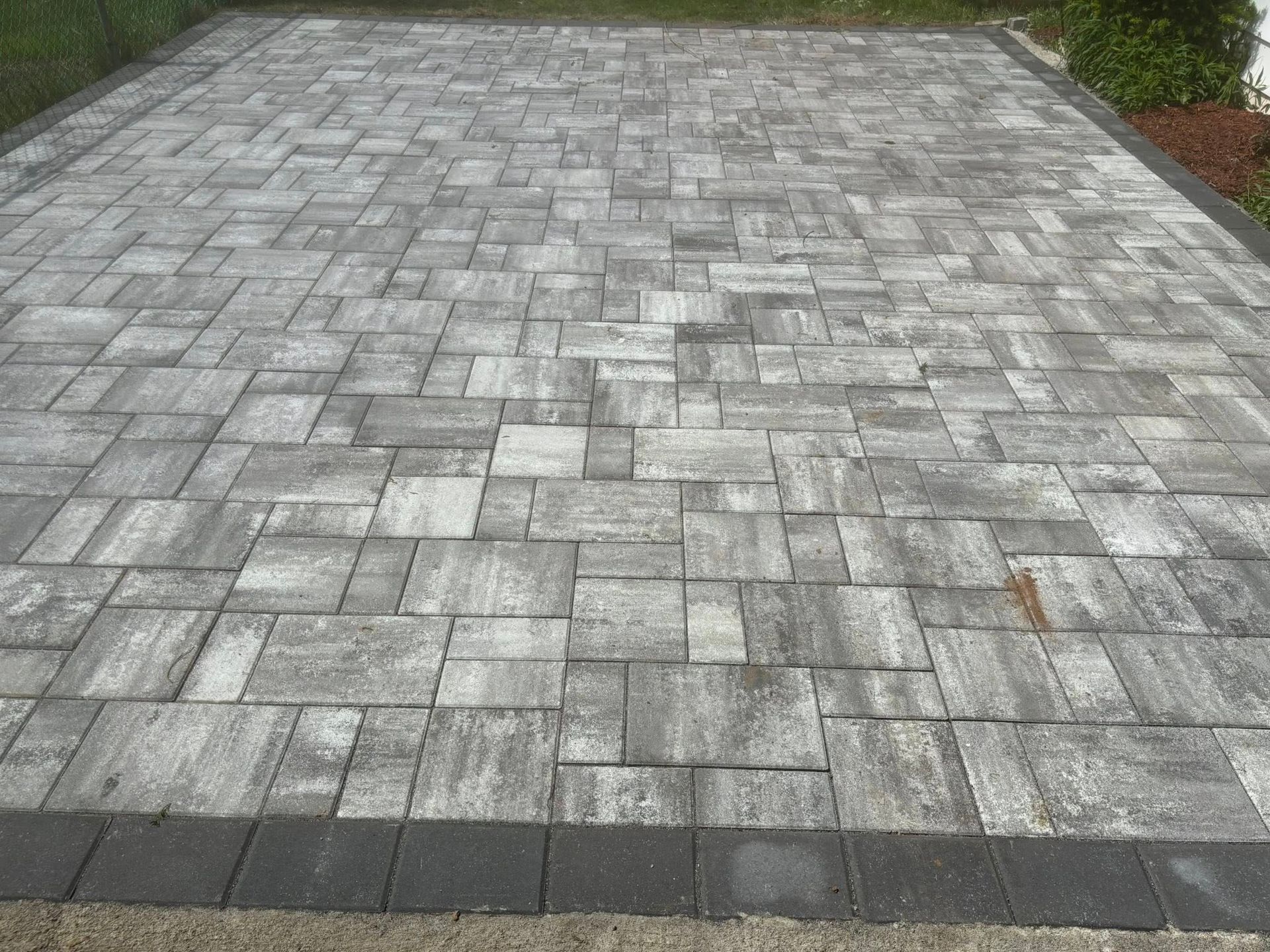 Gray and tan paving stones arranged in a pattern, with a dark border.
