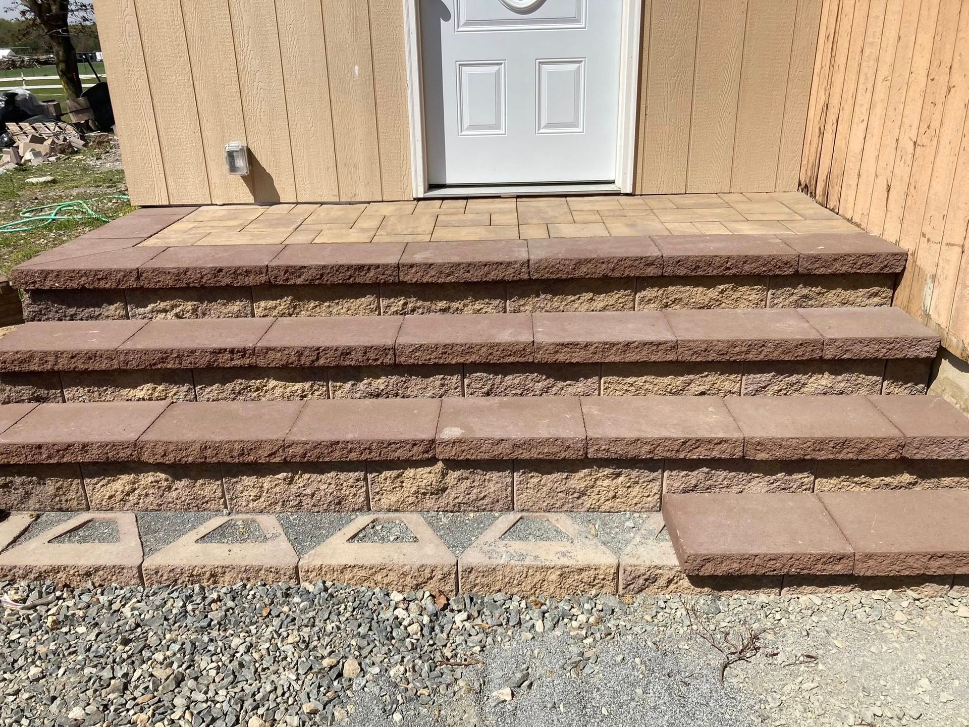 Brick steps leading to a white door; brown and tan bricks; gravel below.