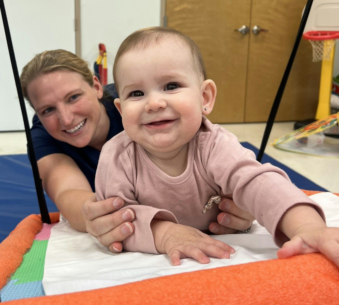 A woman is holding a baby on a swing and the baby is smiling for the camera.