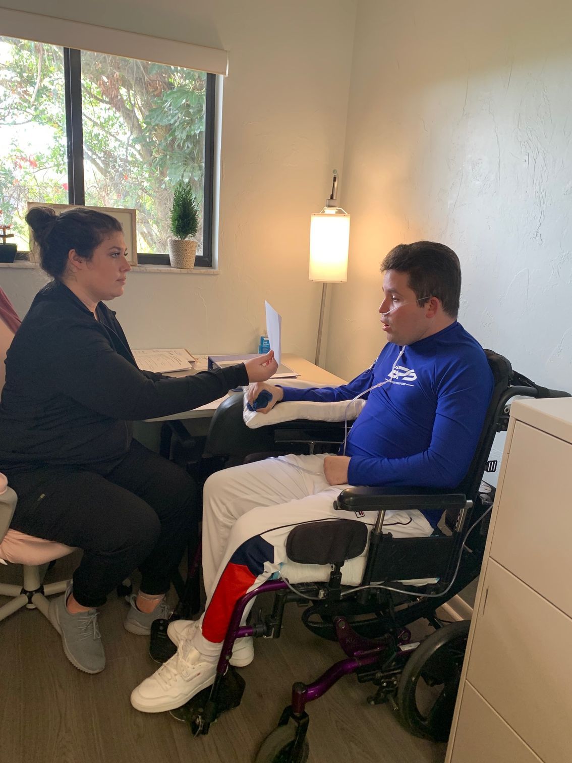 A man in a wheelchair is sitting at a table with a woman.