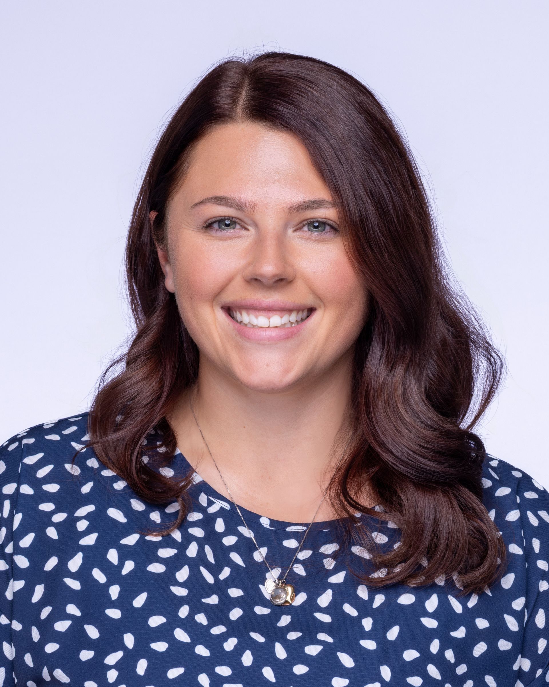 A man wearing glasses and a blue shirt is smiling for the camera.