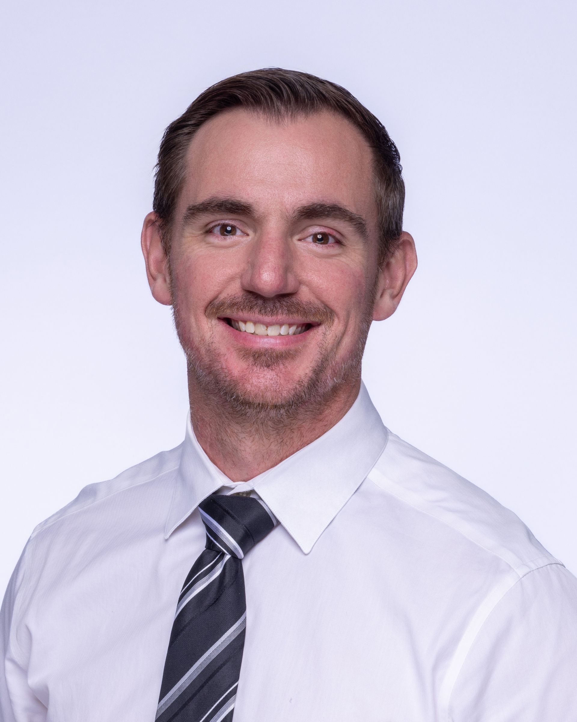 A bald man with a beard wearing a suit and white shirt