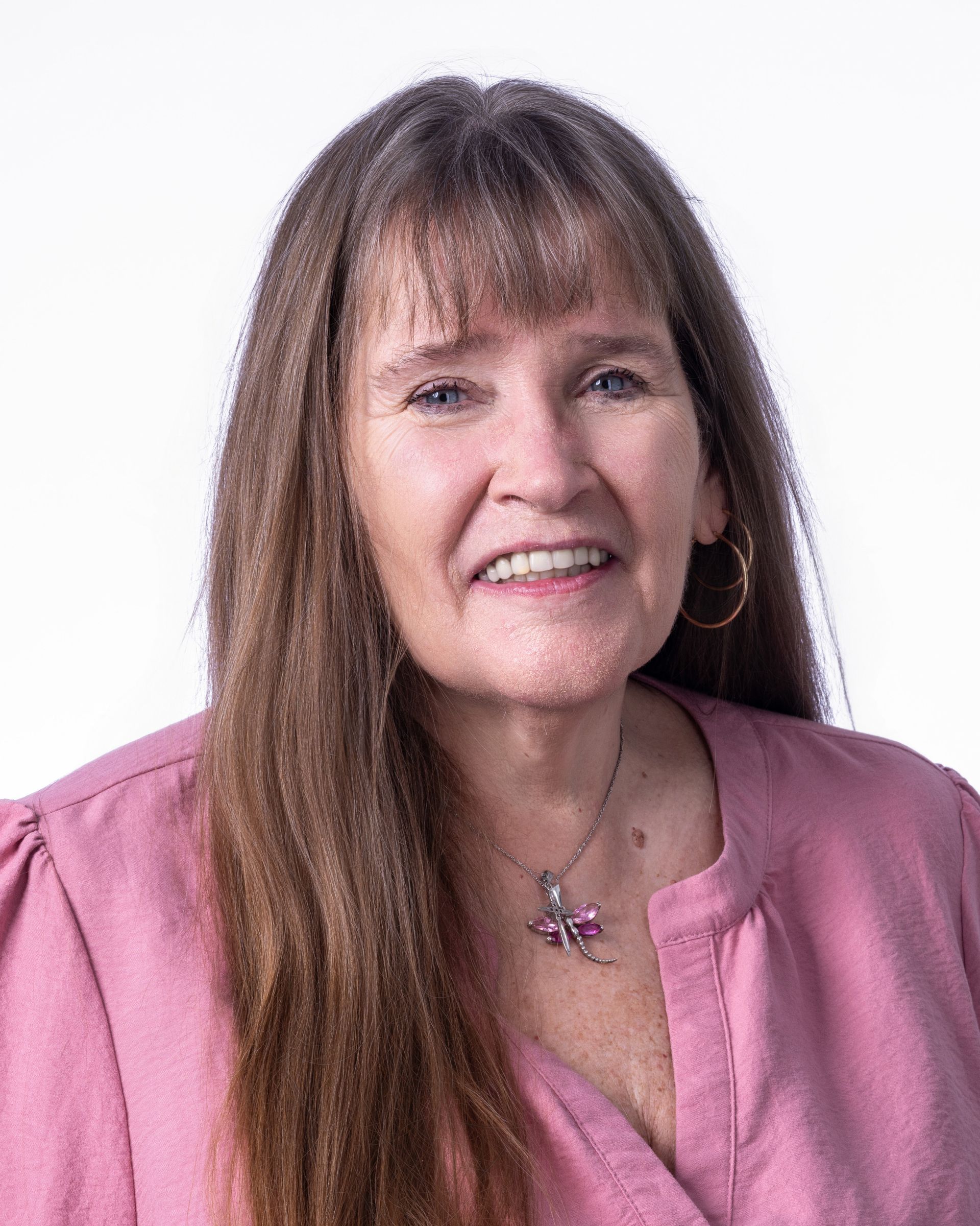 A man wearing glasses and a blue shirt is smiling for the camera.
