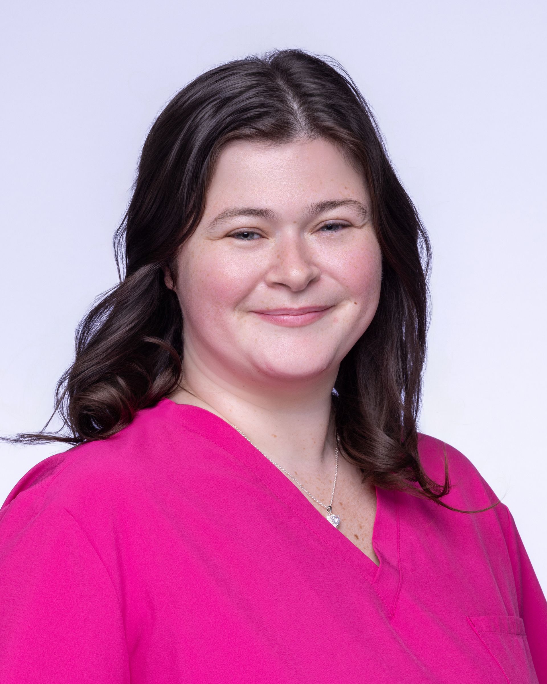 A woman wearing glasses and earrings is standing in front of a painting.