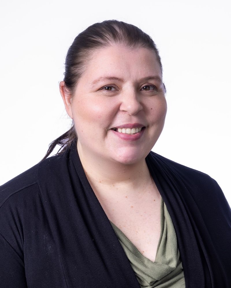 A man wearing glasses and a blue shirt is smiling for the camera.