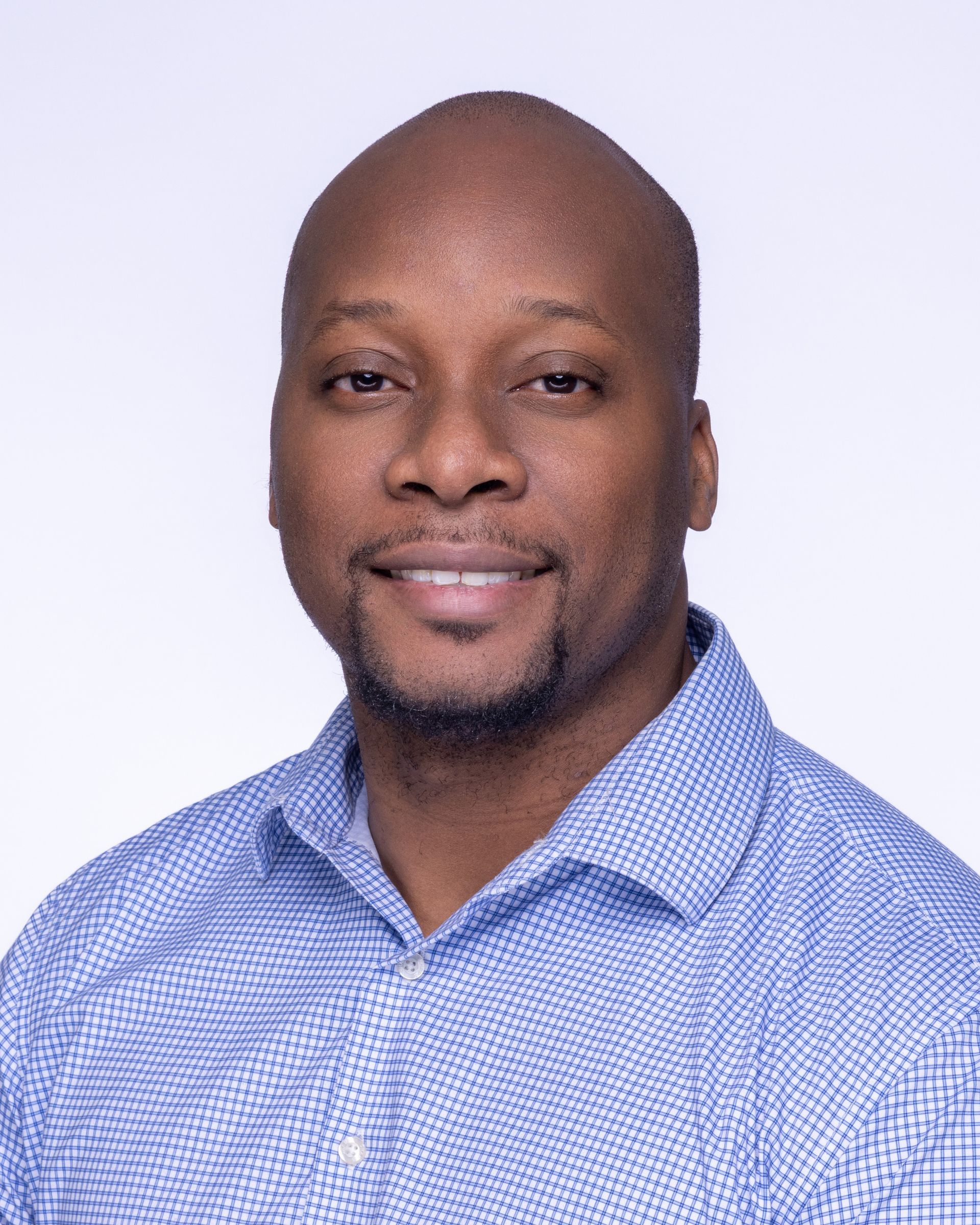A man wearing glasses and a blue shirt is smiling for the camera.