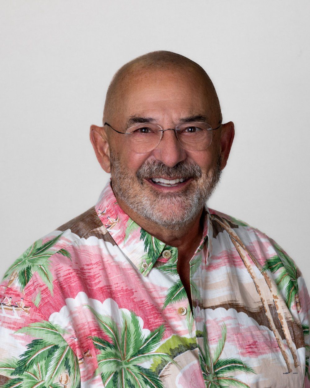 A man wearing glasses and a blue shirt is smiling for the camera.