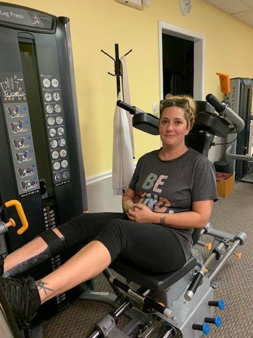 A woman is sitting on a machine in a gym.