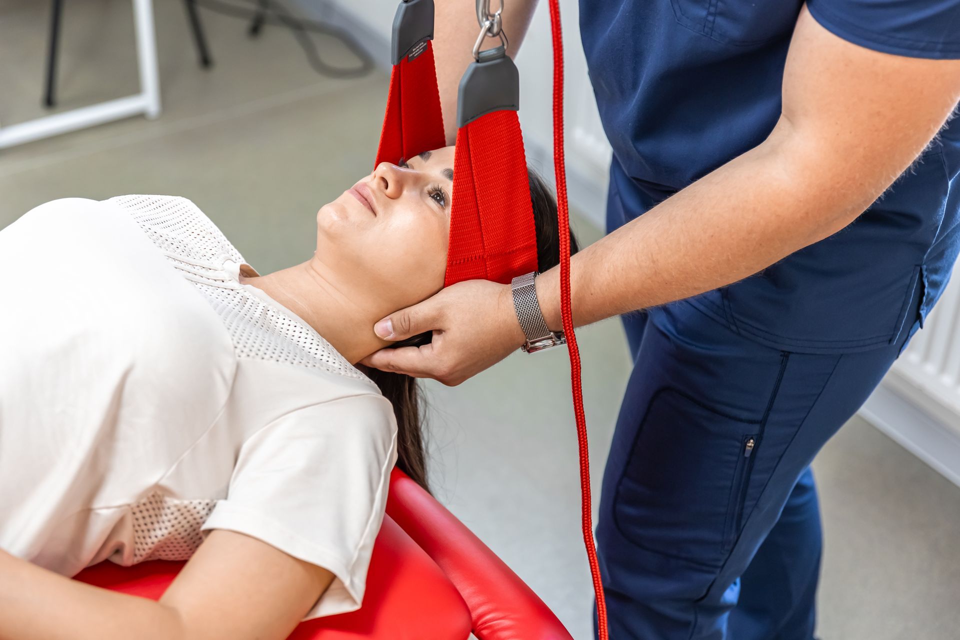 A man and a woman are sitting on the floor in a gym . the woman is bandaging the man 's ankle.