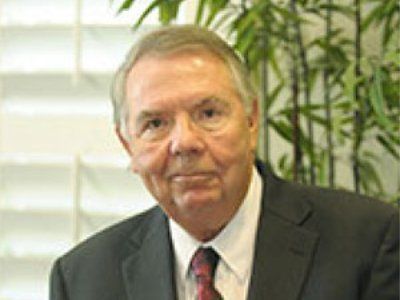 A bald man with a beard wearing a suit and white shirt