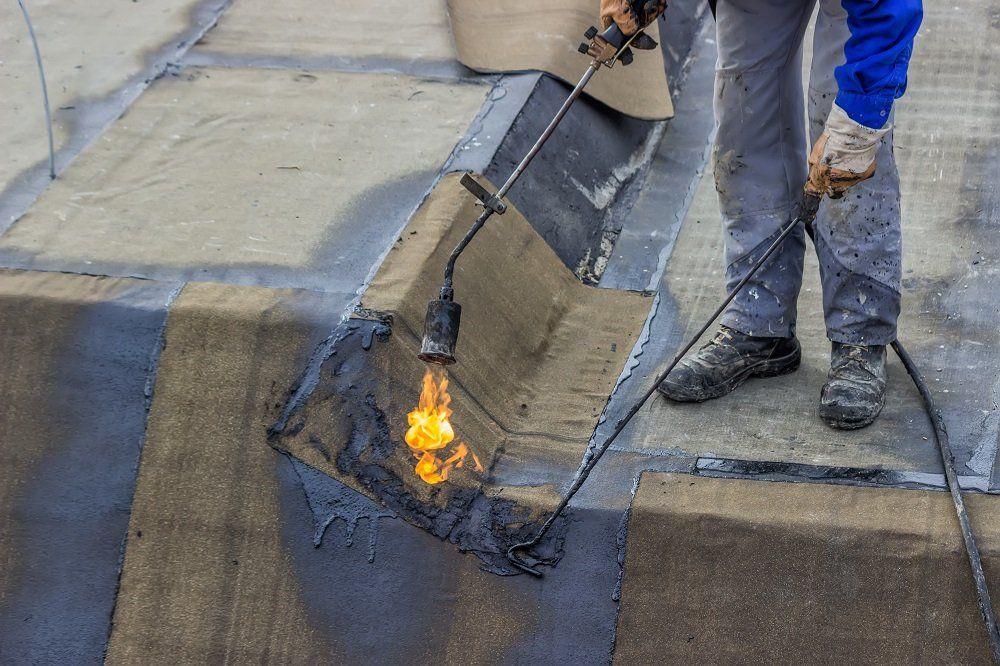 Operaio durante l'impermeabilizzazione di capannoni commerciali