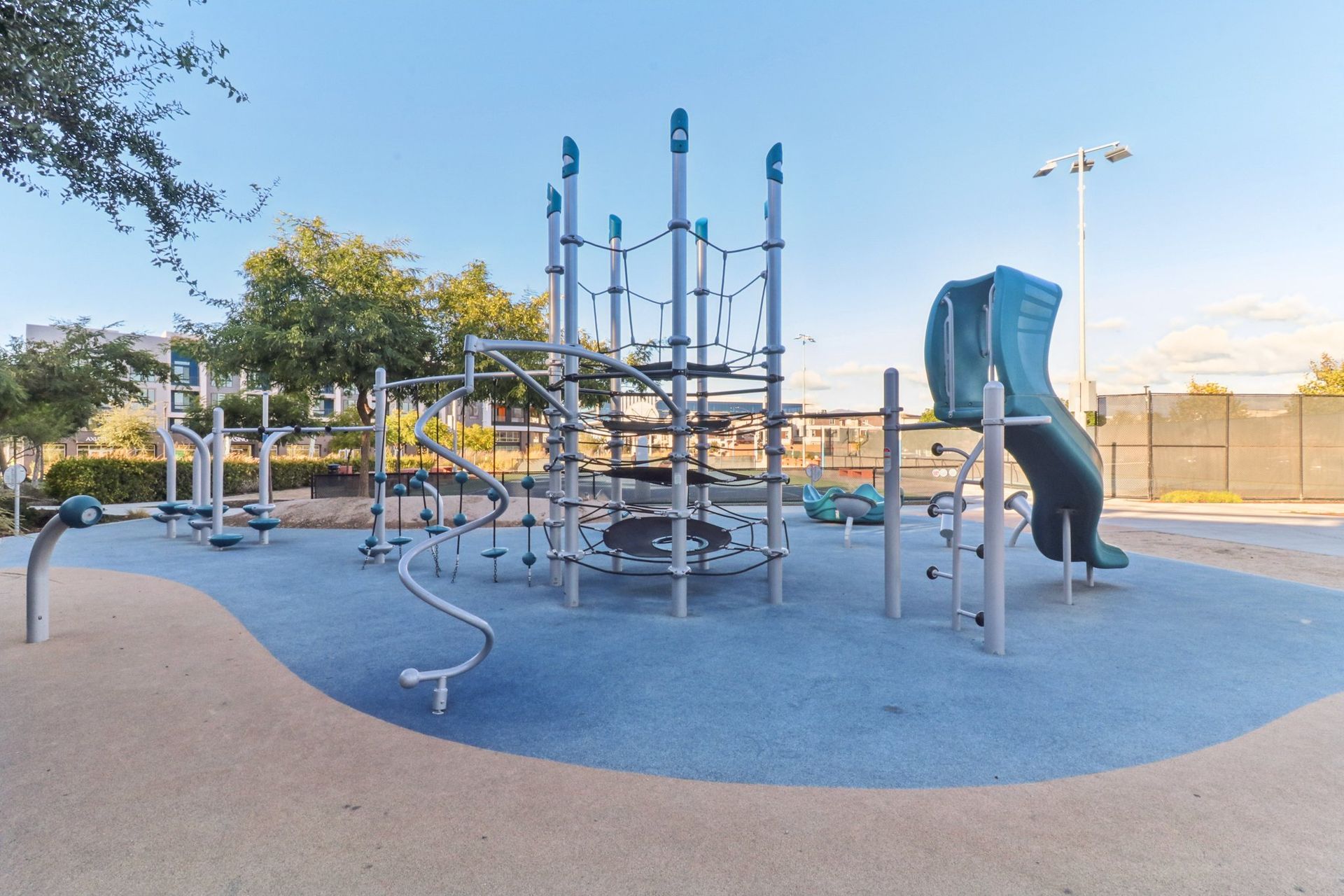 Playground with blue and gray structures and a curved slide on a light blue surface.