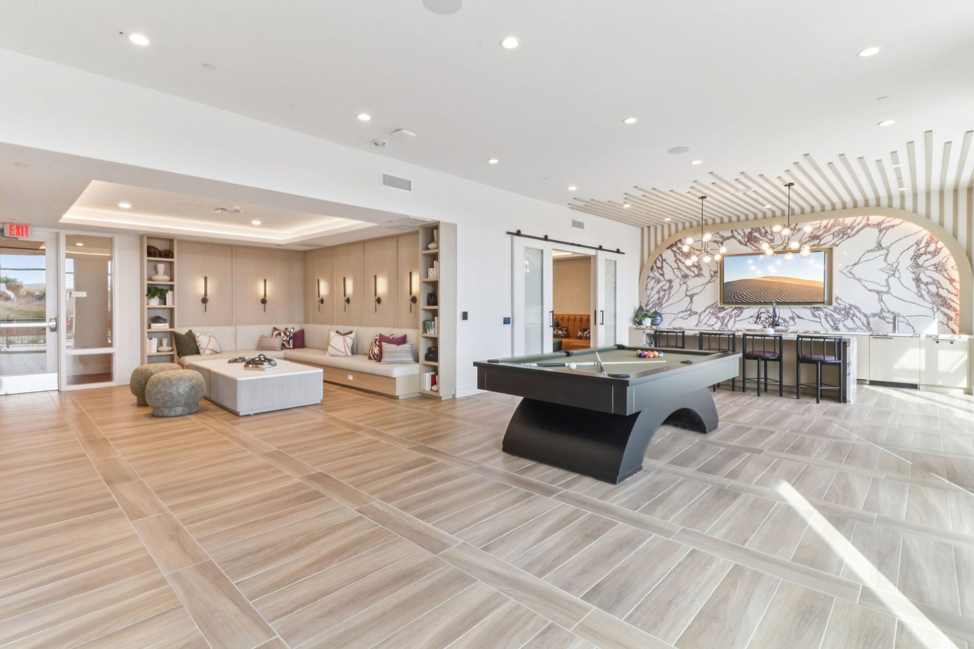 Brightly lit community room with a pool table, seating area, and wall decor.