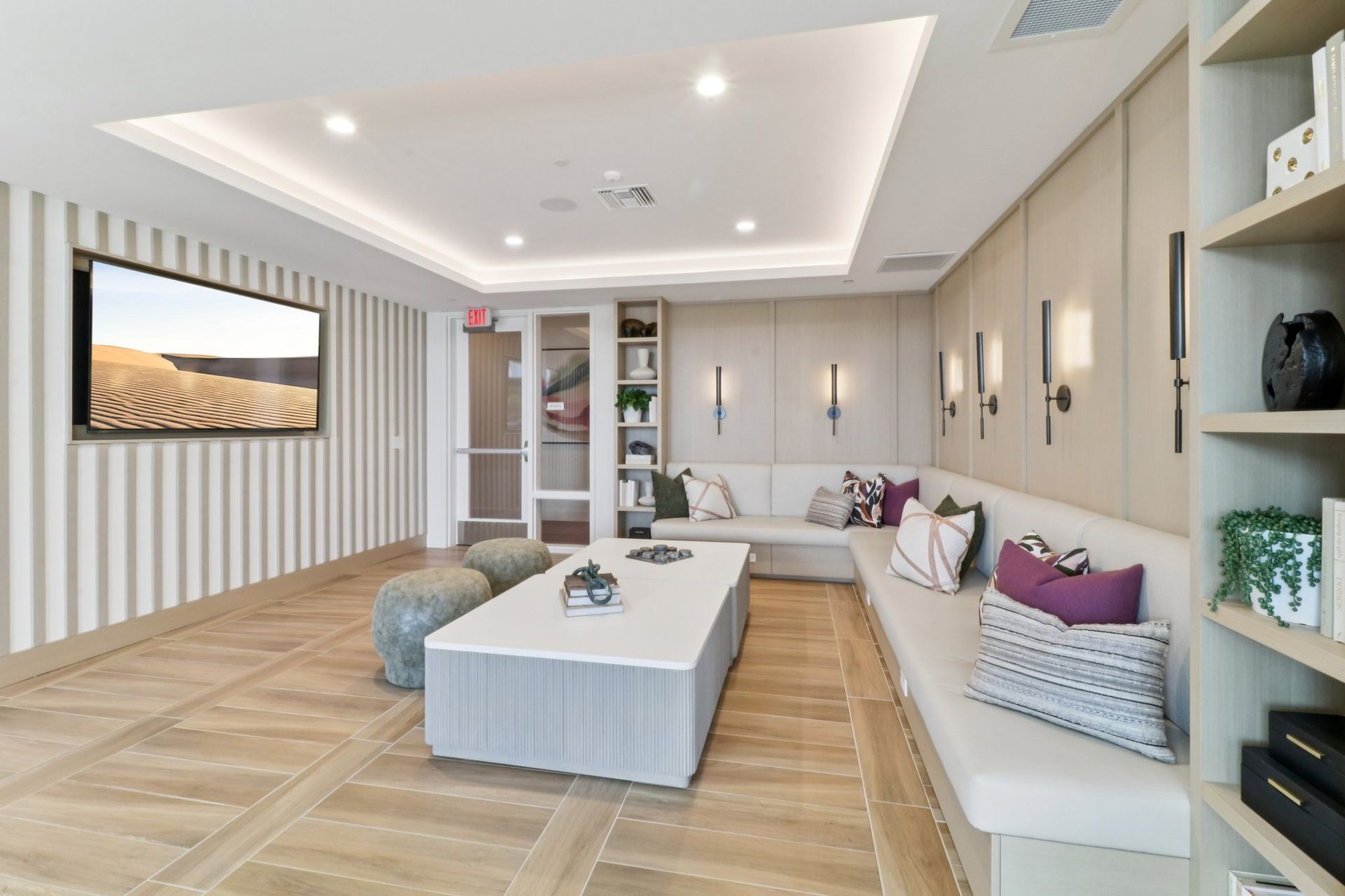 Modern lounge area with a built-in sofa, striped wall, TV, and bookshelf.