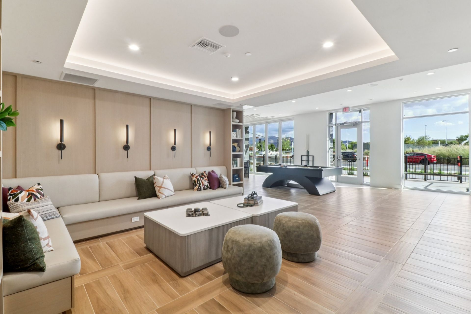 Modern lounge area with neutral tones, sofa, coffee table, and large windows.