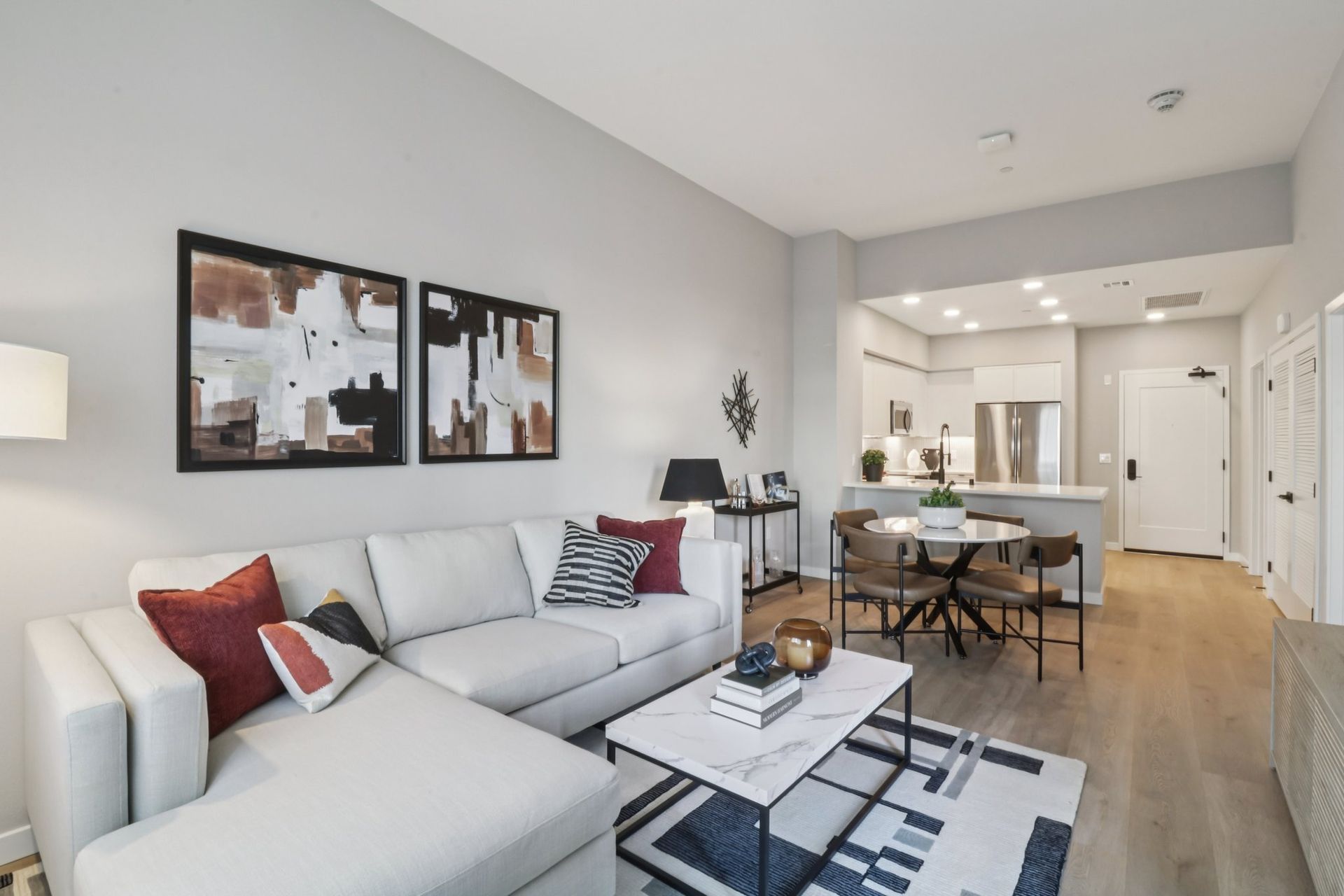 Modern living room with sectional sofa, dining area, and kitchen visible.