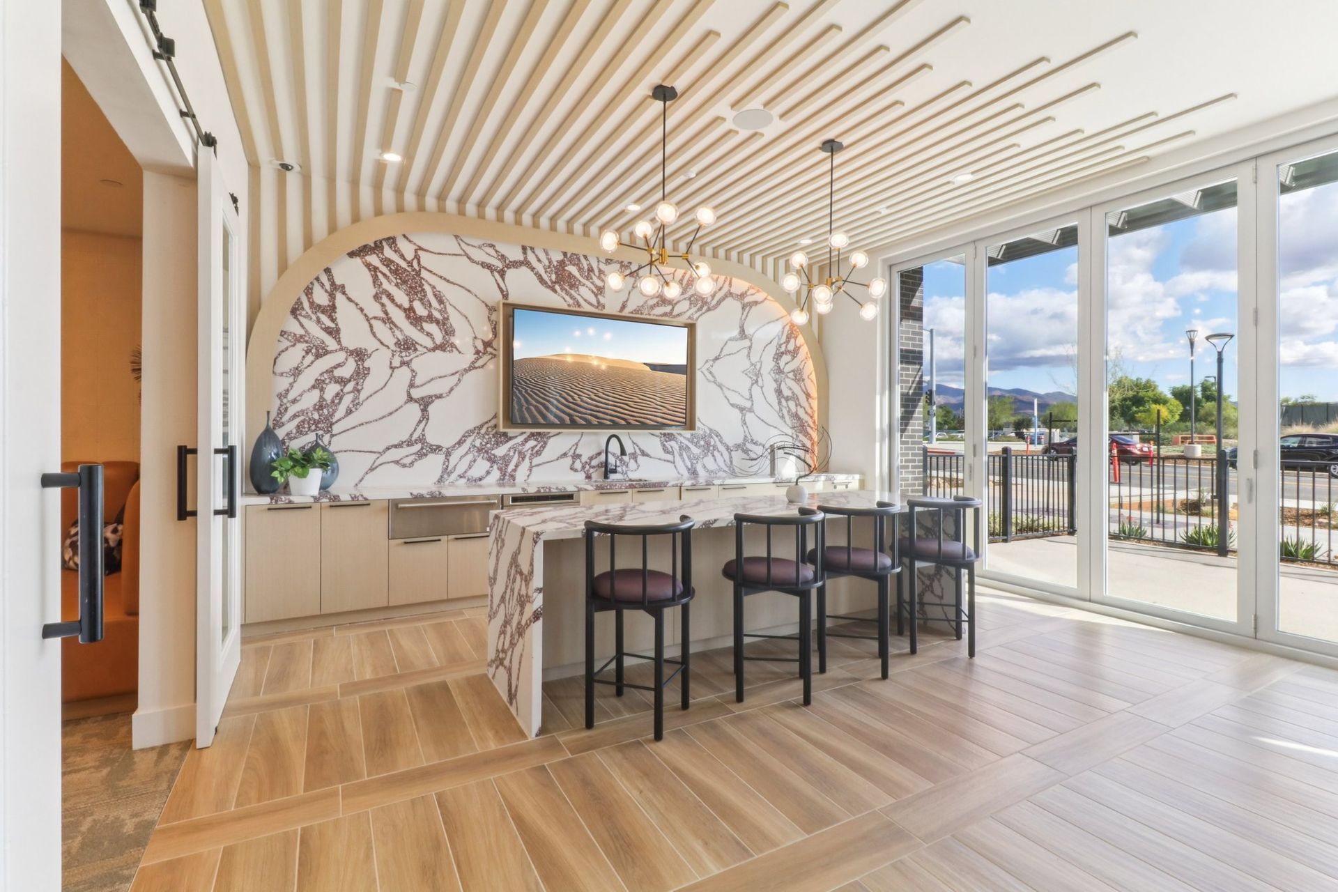 Modern lounge with bar seating, marble accents, and large windows with outdoor views.