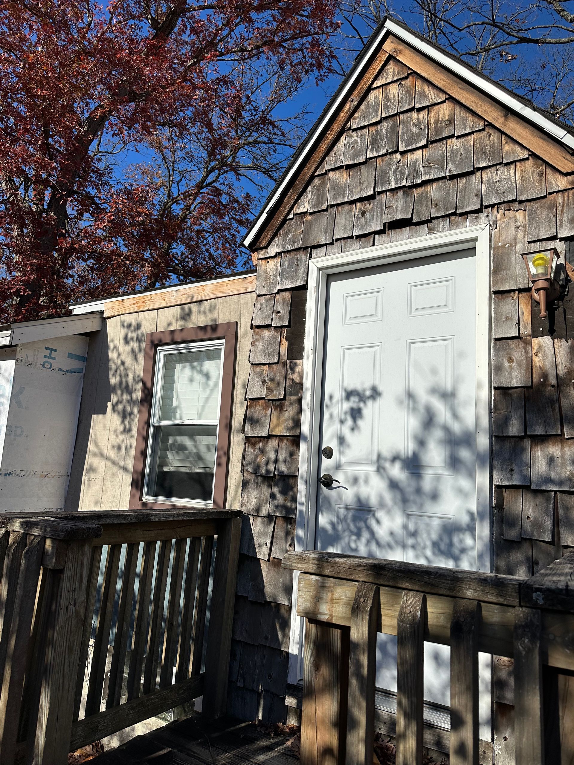 A small house with a white door and a wooden deck.