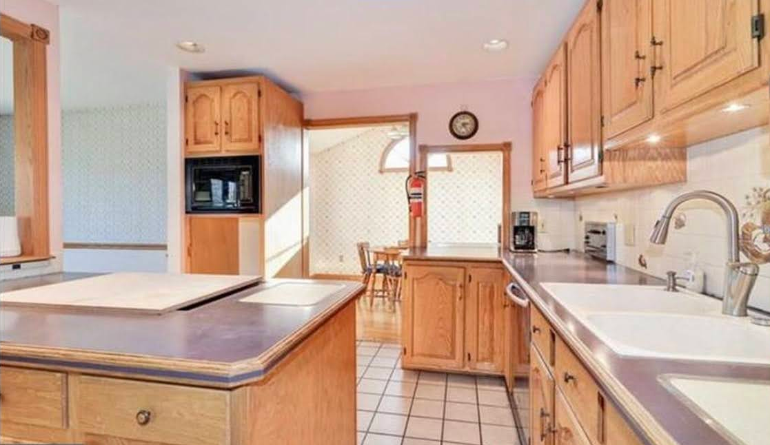 A kitchen with wooden cabinets , a sink , and a clock on the wall.