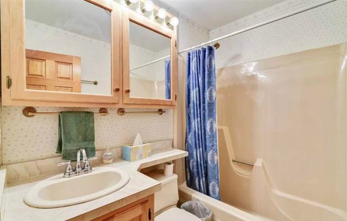 A bathroom with a sink , toilet , shower and mirror.