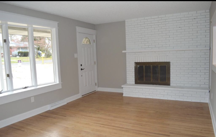 An empty living room with a fireplace and windows